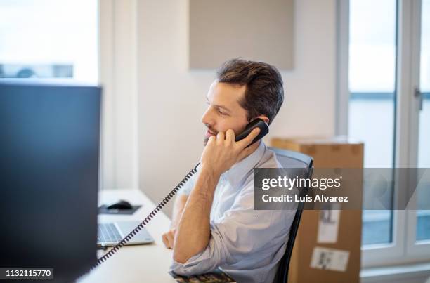 businessman at his desk in office talking over telephone. - mann berater stock-fotos und bilder