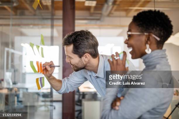 business professionals brainstorming using adhesive notes - fun stock-fotos und bilder