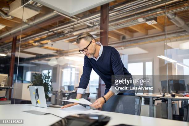 businessman reviewing few reports in office - ceo desk stock-fotos und bilder