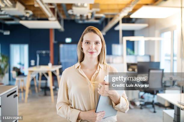 portrait of confident young woman in office - holding laptop stock pictures, royalty-free photos & images