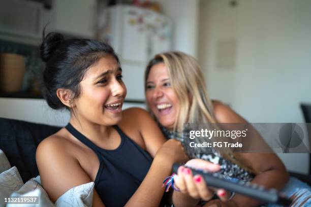 mother and daughter watching tv while have fun on the sofa - 2 people playing joke imagens e fotografias de stock