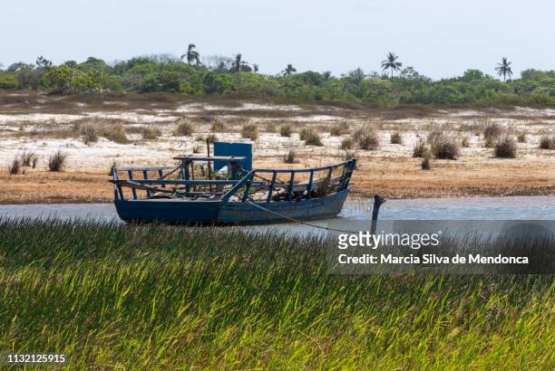 a simple blue fishing boat is moored on the banks of the blue lagoon in jericoacoara. - azul escuro azul stockfoto's en -beelden
