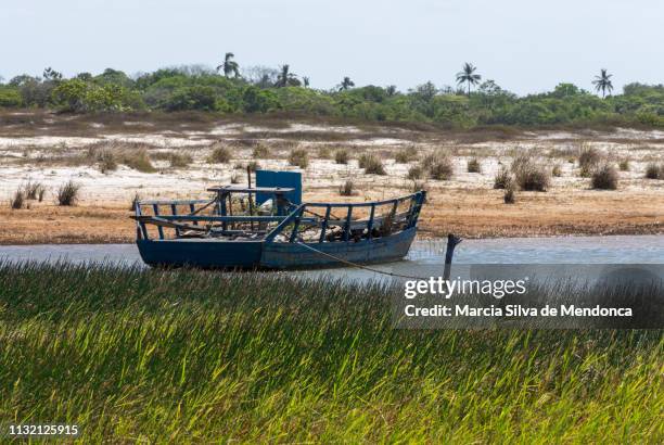 a simple blue fishing boat is moored on the banks of the blue lagoon in jericoacoara. - cor verde stock pictures, royalty-free photos & images