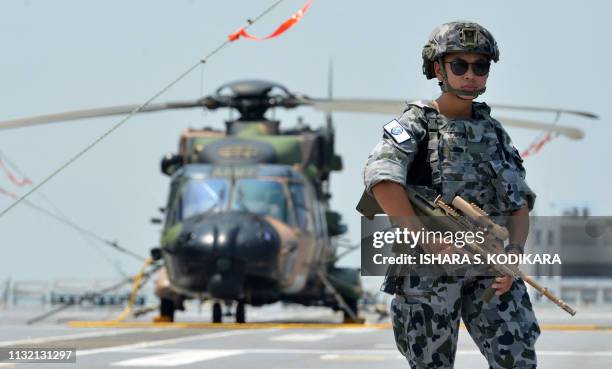 Royal Australian Navy personnel stands guard during a guided tour of HMAS Canberra at the main port in the Sri Lankan capital Colombo on March 23,...