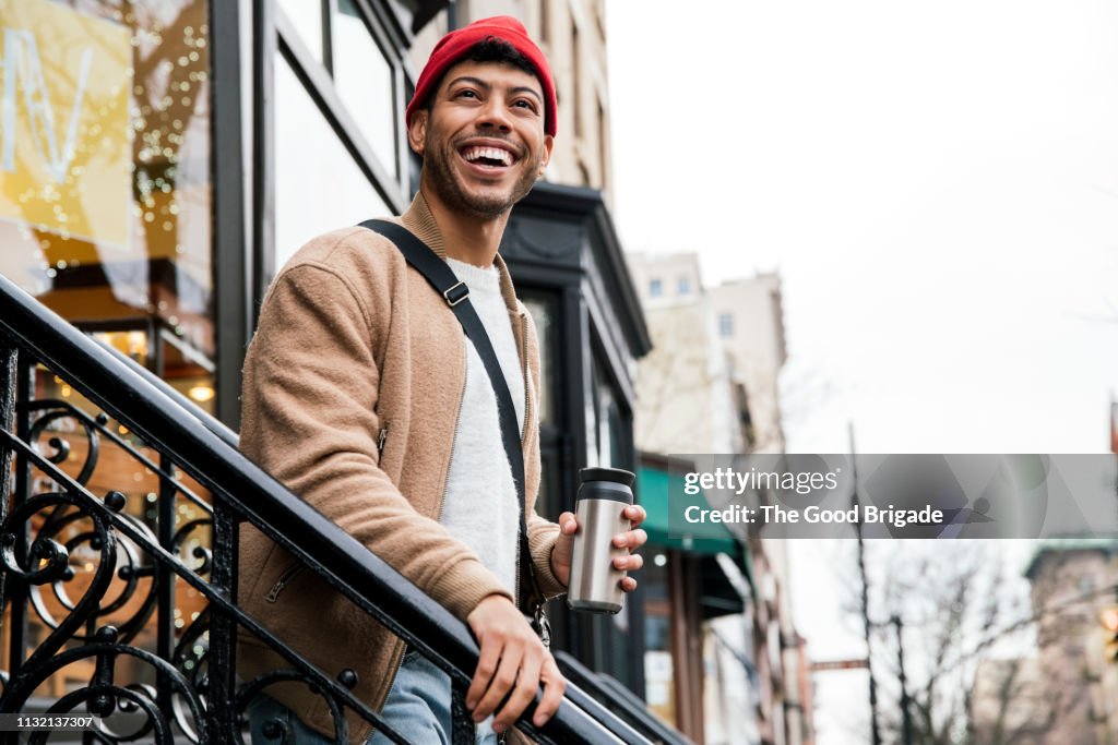 Smiling young man walking down stairs in city