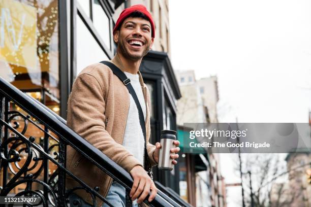 smiling young man walking down stairs in city - crossbody bag bildbanksfoton och bilder