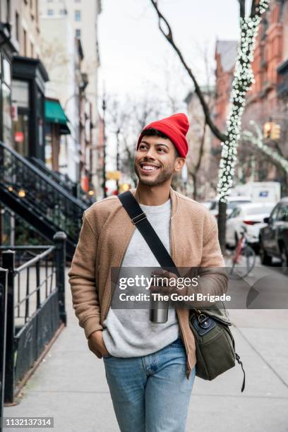 Young man in red cap walking down city street