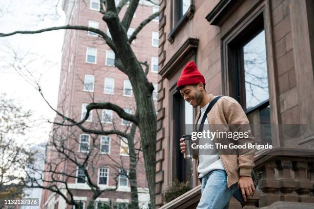 cheerful young man walking down steps at brownstone - man leaving stock pictures, royalty-free photos & images