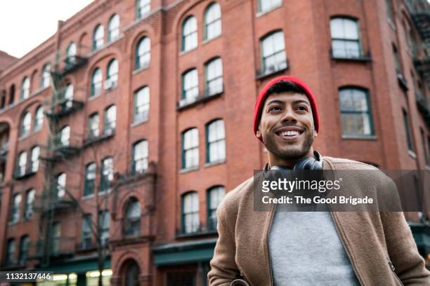 low angle view of young man standing on city street - latino men stock-fotos und bilder