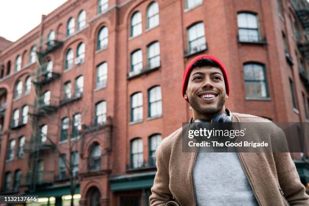 low angle view of young man standing on city street - millenials fotografías e imágenes de stock