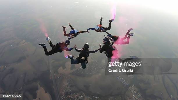 skydiving team work formation with pink smoke - aerial stunts flying stock pictures, royalty-free photos & images