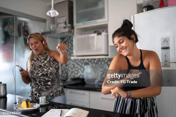 mother and daughter having fun together while dancing in the kitchen - family teenager home life stock pictures, royalty-free photos & images