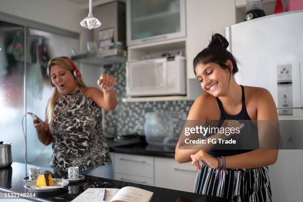 mother and daughter having fun together while dancing in the kitchen - girl singing imagens e fotografias de stock