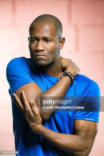 mature bald black man dealing with a shoulder injury - man touching shoulder imagens e fotografias de stock
