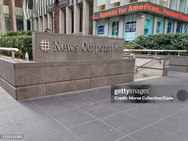 Sign on facade at entrance to office of News Corporation, with ticker in background reading Agenda for Americans, Donald Trump, in Manhattan, New...