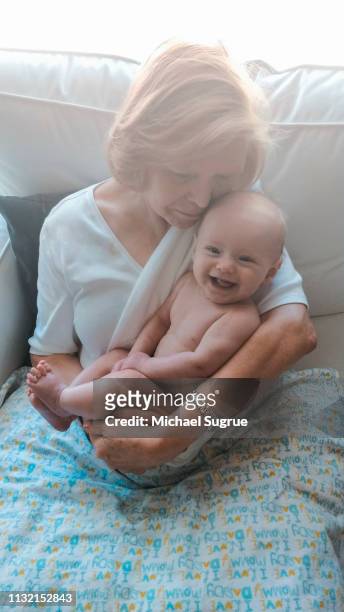 Grandmother holding smiling newborn granddaughter.
