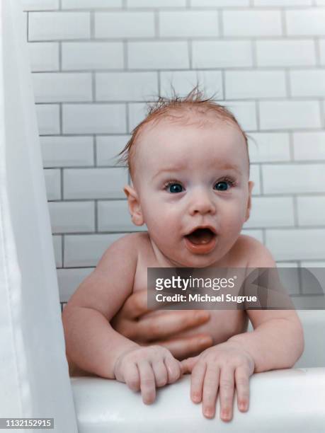 Surprised newborn baby in bathtub.
