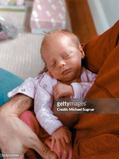 Newborn baby sleeping in parent's arms.