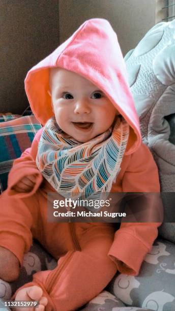 Smiling newborn baby in pink outfit.