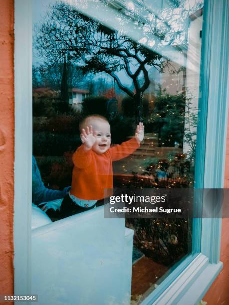 Smiling newborn baby looking out window.