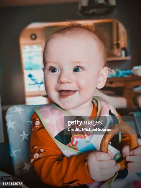 Smiling newborn baby in high chair.