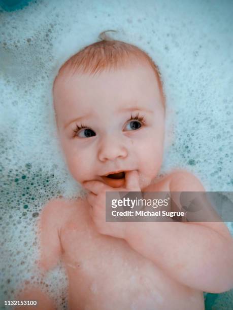 Smiling newborn baby in bathtub.