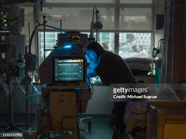 A mother watches her baby in an isolet with hyperbillirubinemia in the neonatal intensive care unit of a hospital.