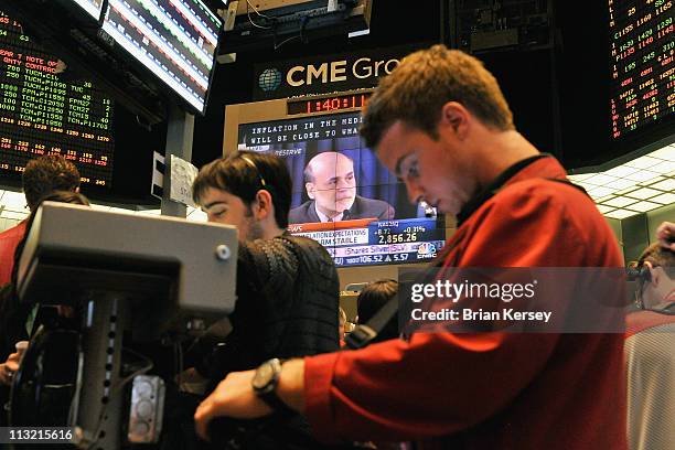 Trader looks at his computer screen as Federal Reserve Chairman Ben Bernanke is shown on a large television screen at the CME Group in Chicago on...