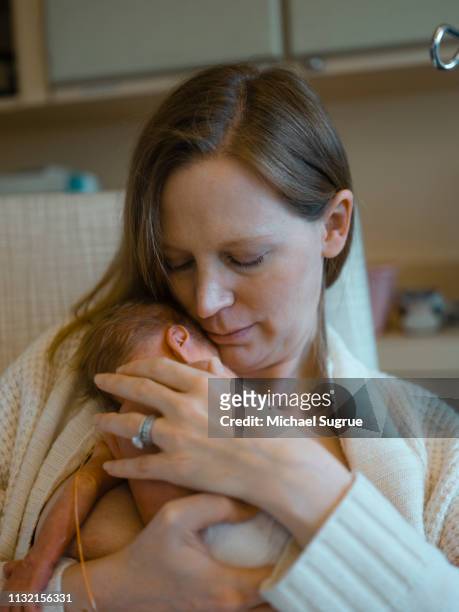 A mother tenderly holds her newborn baby at the hospital.