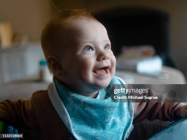 An infant child laughs while playing at home.