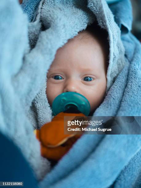 A newborn baby swaddled in a beach towel.