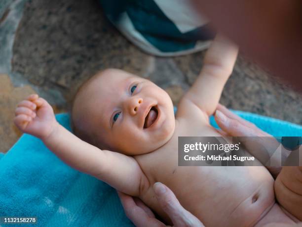 A newborn baby smiles while lying down on a towel.