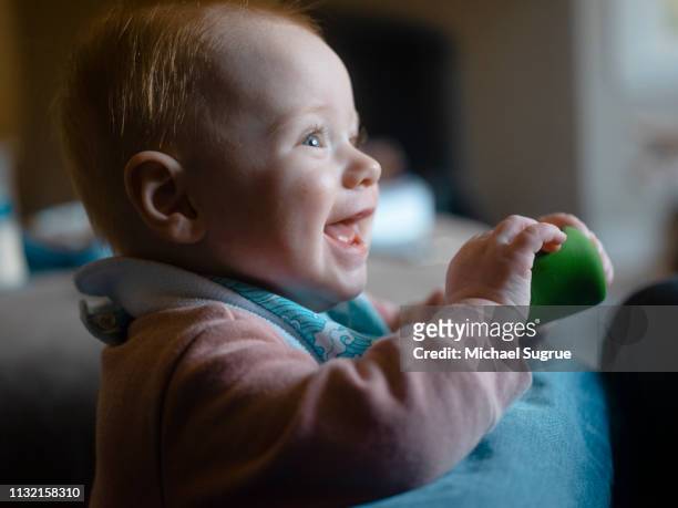 An infant child laughs while playing at home.