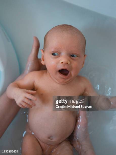 A newborn baby takes a bath.