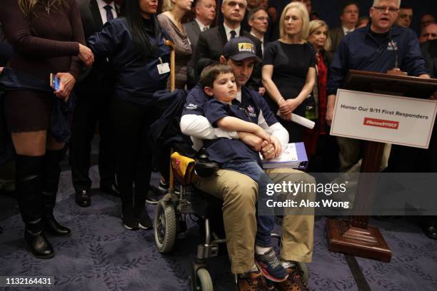 Robert Serra, a 9/11 responder, listens with his son Vincent during a news conference February 25, 2019 on Capitol Hill in Washington, DC. Joined by...