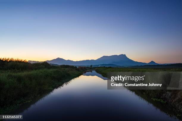 mount kinabalu view at sunrise from farm water irrigation canal - green vanishing point stock pictures, royalty-free photos & images