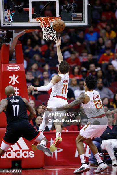 Trae Young of the Atlanta Hawks drives to the basket past PJ Tucker of the Houston Rockets as John Collins of the Atlanta Hawks looks on at Toyota...