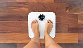 Woman bare feet standing on a digital scale with body fat analyzer