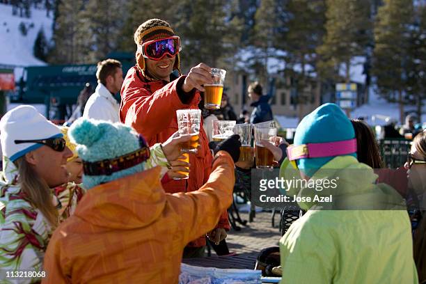 friends in ski gear socialize and enjoy a beer on the deck on a sunny day on the mountain. - mountains alcohol snow bildbanksfoton och bilder