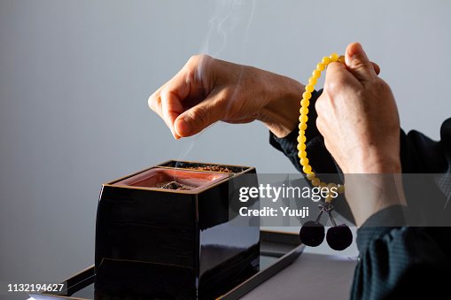 De ceremonie van de begrafenis van Japan. De vrouw van de Senior brandwonden wierook voor de ziel van de overledene in een zwarte rouw jurk. De ceremonie van de begrafenis van Japan. De vrouw van de Senior brandwonden wierook voor de ziel van de overledene in een zwarte rouw jurk.