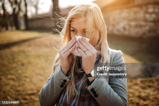 bionda malata che si soffia il naso - allergie foto e immagini stock