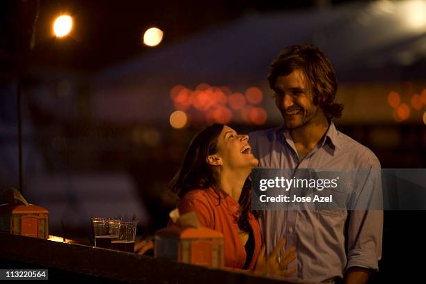 a young couple laughs and chats as they enjoy a beer on the deck of a local bar on the waterfront at casco bay harbor in portland, me. - date night romance stock-fotos und bilder