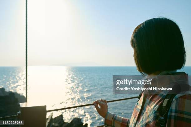 japanese woman on journey to enjoy the scenery of the sea.who standing on the suspension bridge. - ito stock pictures, royalty-free photos & images