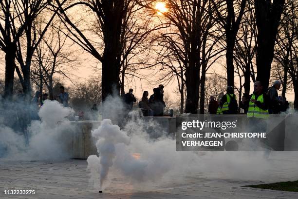 Yellow Vest protesters stand close to a smoke canister during an anti-government demonstration called by the 'Yellow Vest' movement in Metz, on March...