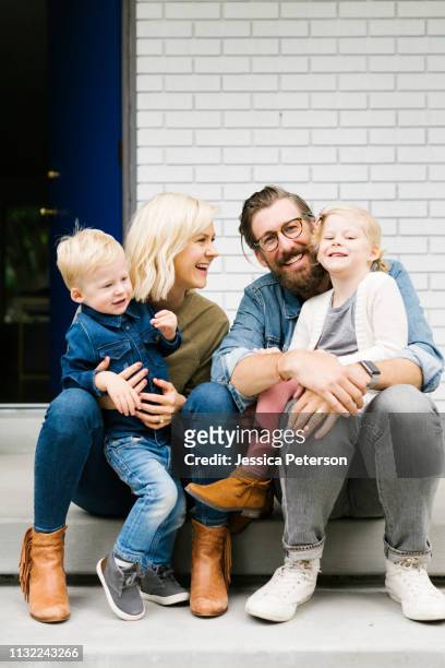 family sitting together on front step of their house - family smiling at front door stock pictures, royalty-free photos & images