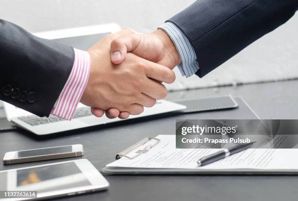 close-up image of a firm handshake between two colleagues after signing a contract - business mann anzug geschäftlicher hintergrund stock-fotos und bilder