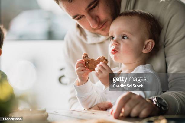 baby boy essen einen gerösteten teekuchen - vaterschaft stock-fotos und bilder