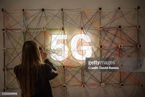 Staff member works next to a 5G logo at the Xiaomi booth on day 2 of the GSMA Mobile World Congress 2019 on February 26, 2019 in Barcelona, Spain....