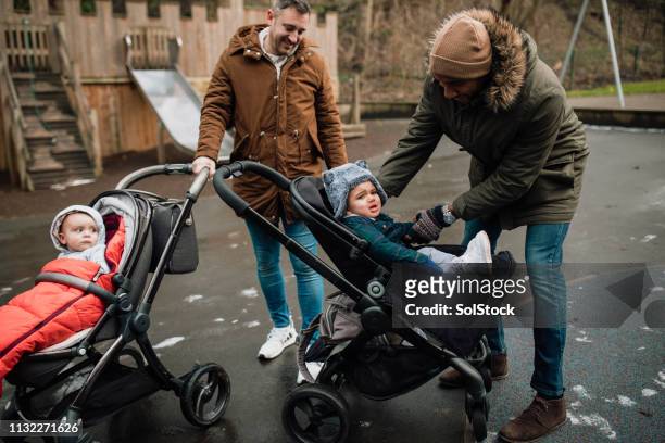 dad putting his son into a baby stroller - play date imagens e fotografias de stock