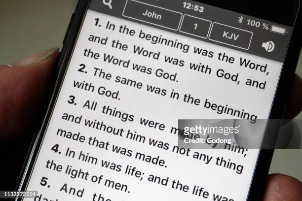 Bible on a smartphone. Man reading the New Testament. Gospel according to John.